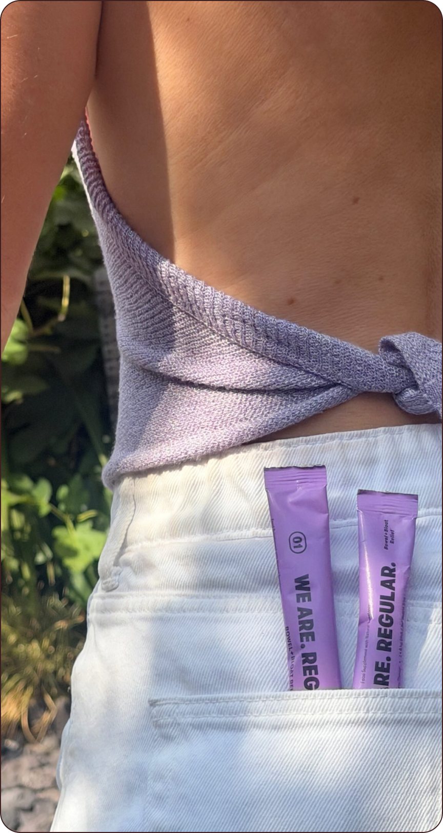 Two Wild Berry sticks of 01. Bowel + Bloat tucked into the back pocket of white jeans