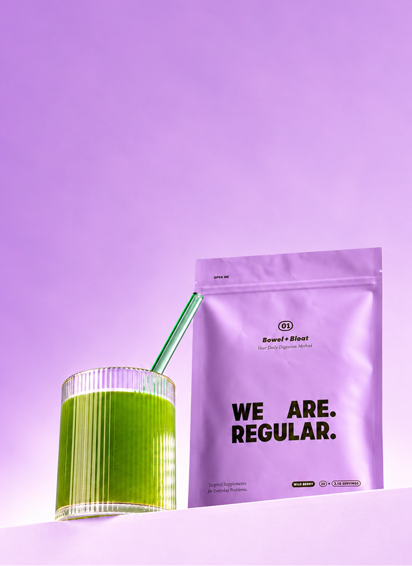 We Are Regular 01 Bowel + Bloat pouch next to a glass of green drink